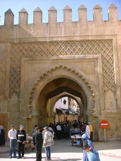The entrance gate to the Mellah of Fes — a horseshoe arch in dressed stone beyond which the character of the city changes completely, marking the threshold between the wider medina and the historic Jewish quarter
